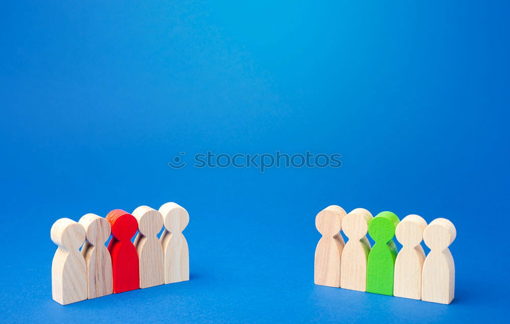 A red playing figure stands together with white playing figures in a circle on a blue background