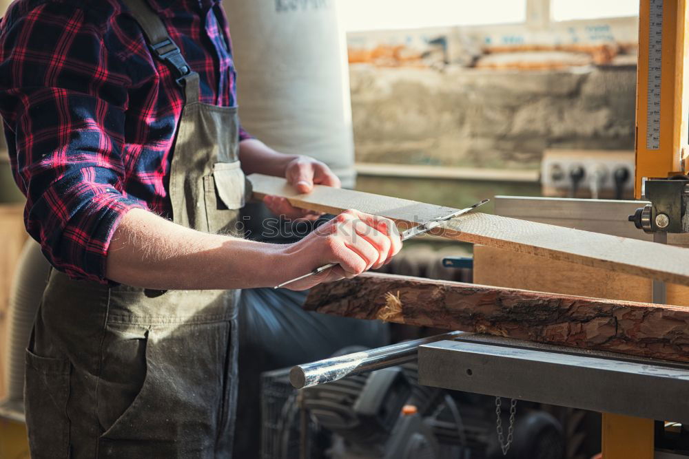 Similar – Carpenter with circular saw cutting a wooden plank