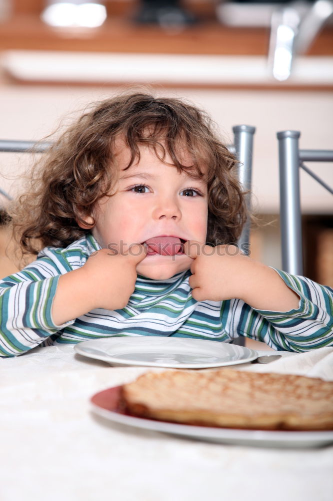 Similar – Little boy in a cafe during lunch. Hungry kid eating sausage from his sandwich