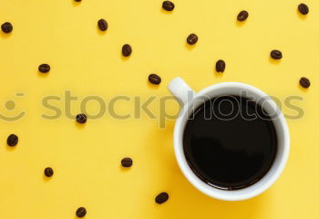 Top view of black coffee and coffee beans on yellow