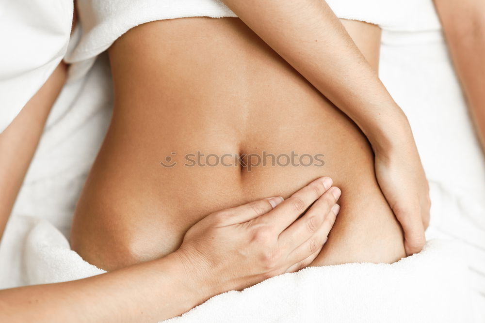 Top view of hands massaging female abdomen.