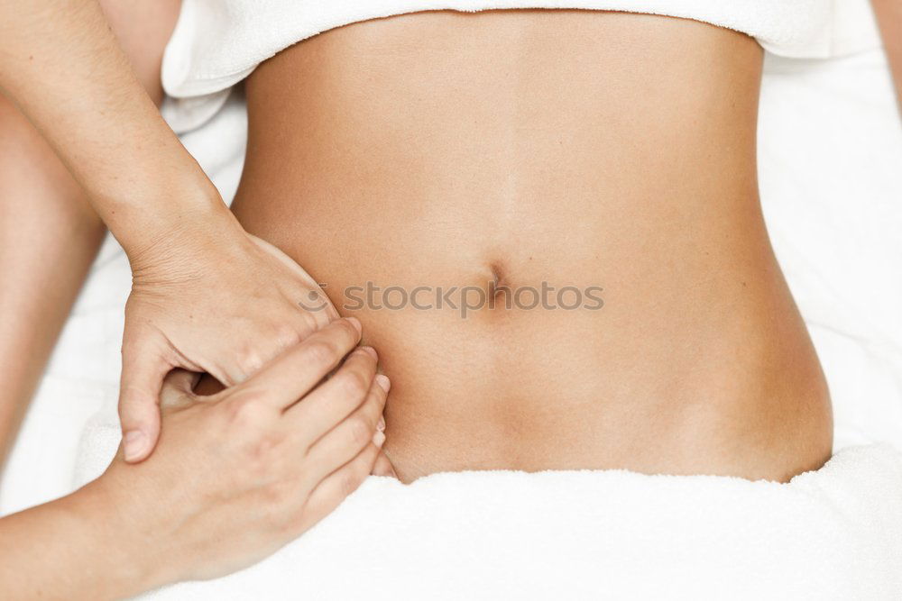 Hands massaging female abdomen.