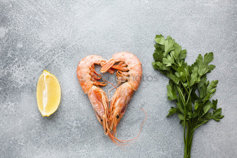 Raw prawn or shrimps and squids on light blue background, decorated with with seaweeds and lemon, top view, flat lay. Seafood cooking concept