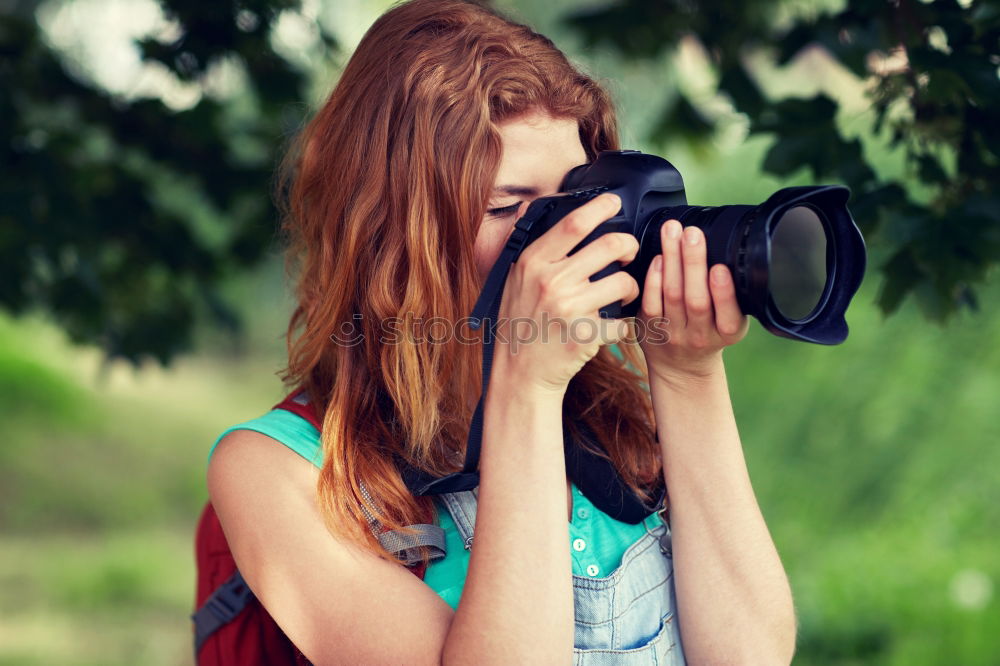 Similar – Smiling young woman using a camera to take photo at the park.