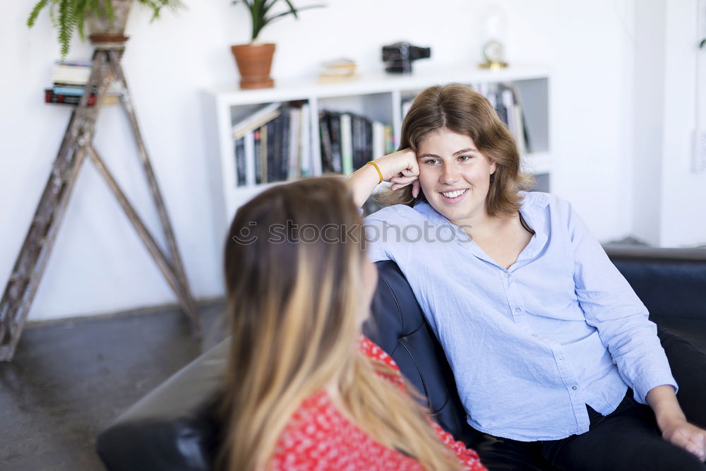 Similar – Image, Stock Photo Two friends talking and laughing on a sofa in the living room at home