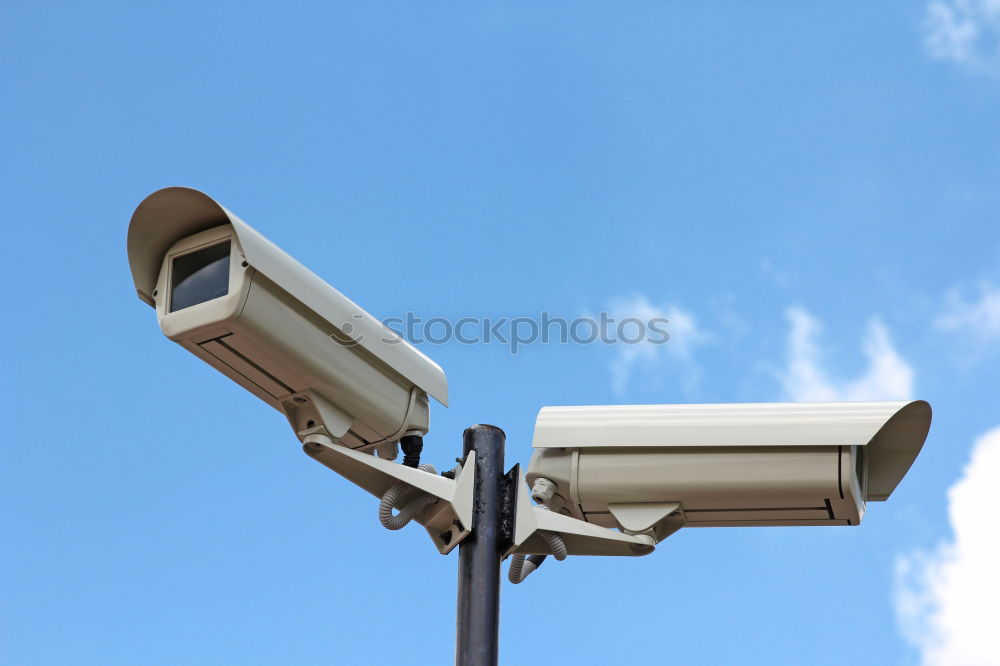 Industrial Security CCTV Camera installed on metal fence. The camera protects the industrial ground. Blue sky is on the background.