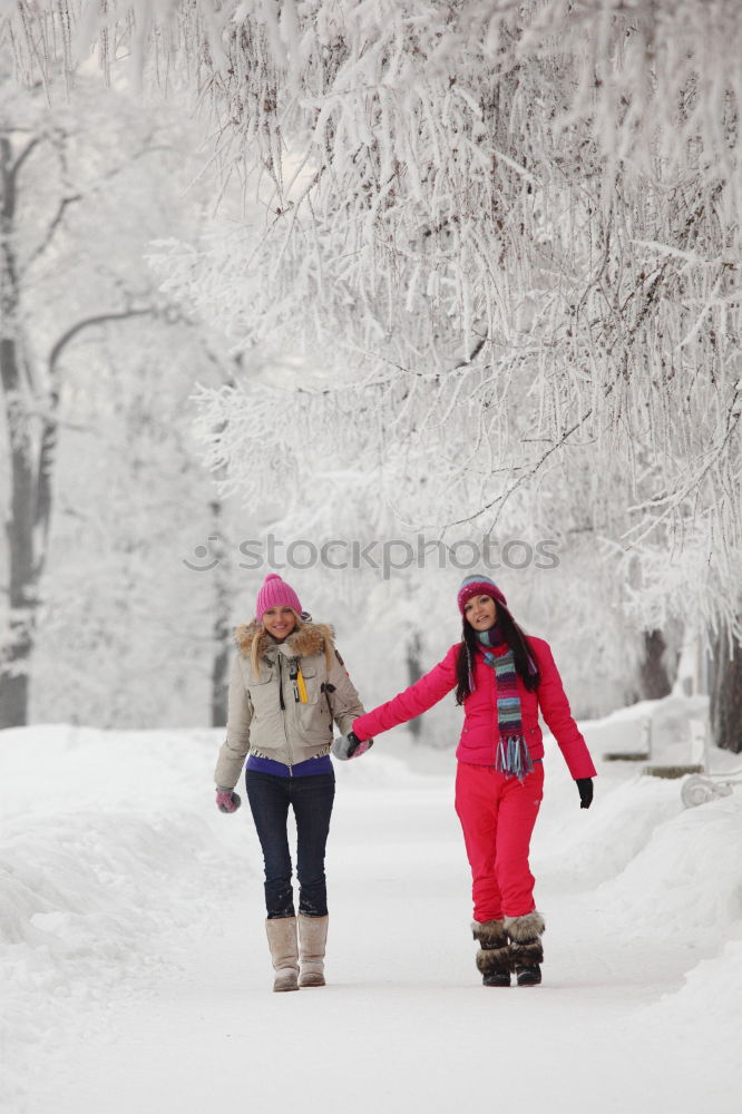 Similar – Family, mother and two daughters, spending time together walking outdoors in winter. Woman is pulling sled with her little daughter, a few years old girl, through forest covered by snow while snow falling, enjoying wintertime. Mother is wearing red winter