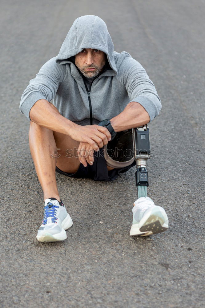 Sporty man sitting with towel and water bottle in gym floor