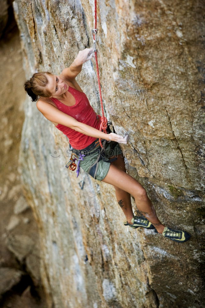 Female climber clinging to a cliff.