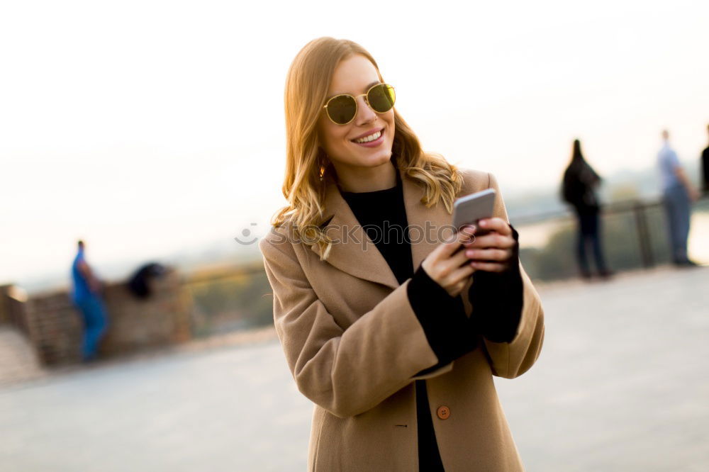 Similar – Young happy woman with green jacket taking selfie with her smartphone on the beach at sunset