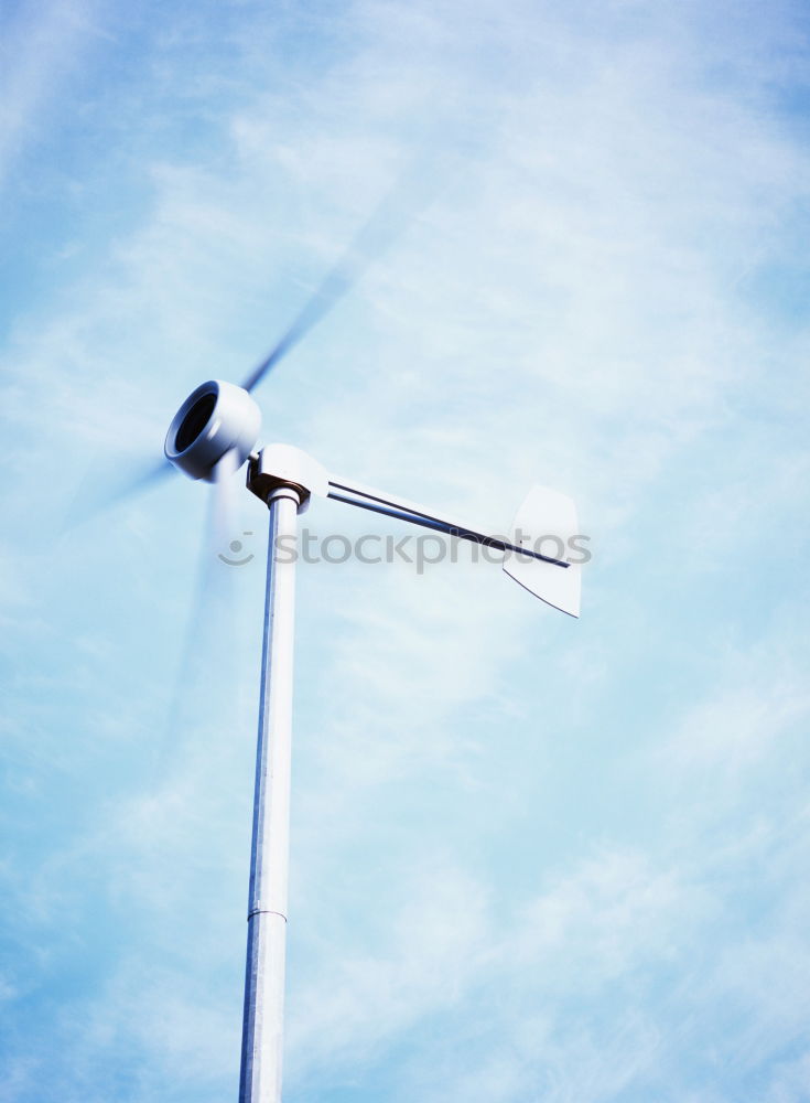 Windkraftanlage vor blauem Himmel mit Wolken an einem Rapsfeld