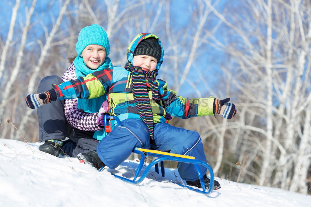 Young family with children go sledding in winter sunshine