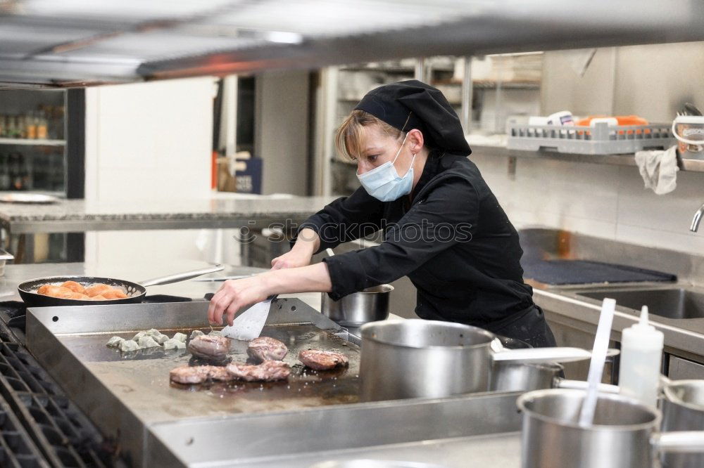 Similar – A cook in a restaurant wearing a mask as a precaution against the coronavirus preparing the meal.