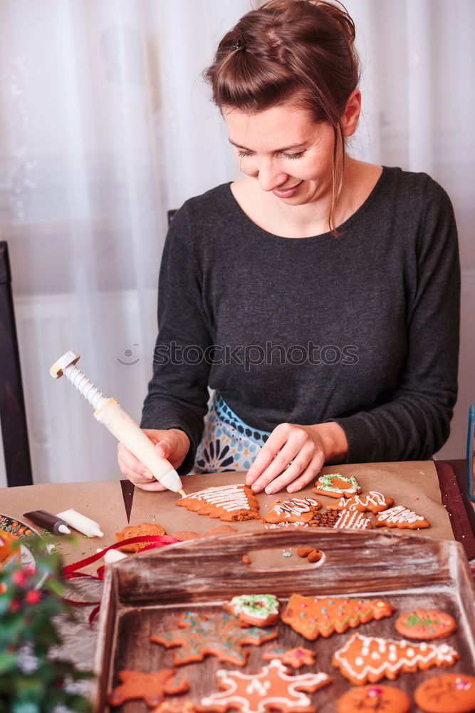 Woman decorating baked Christmas gingerbreads with frosting