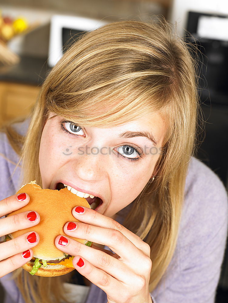 Similar – Woman taking bite of hamburger in restaurant