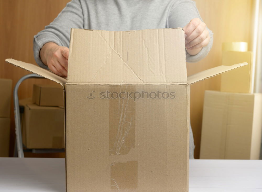 Foto Bild Eine junge Frau öffnet neugierig und voller Vorfreude ein Paket