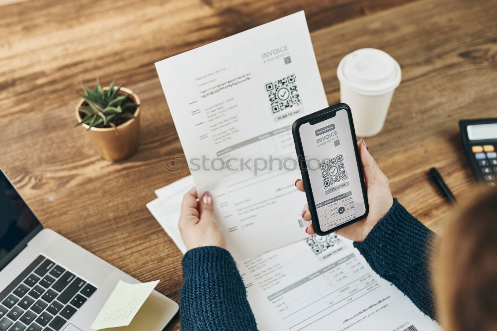 Woman paying invoice scanning QR code from document using fast secure payment system and smartphone QR scanner. Business woman paying bills using express payment technology. Paying expenses online