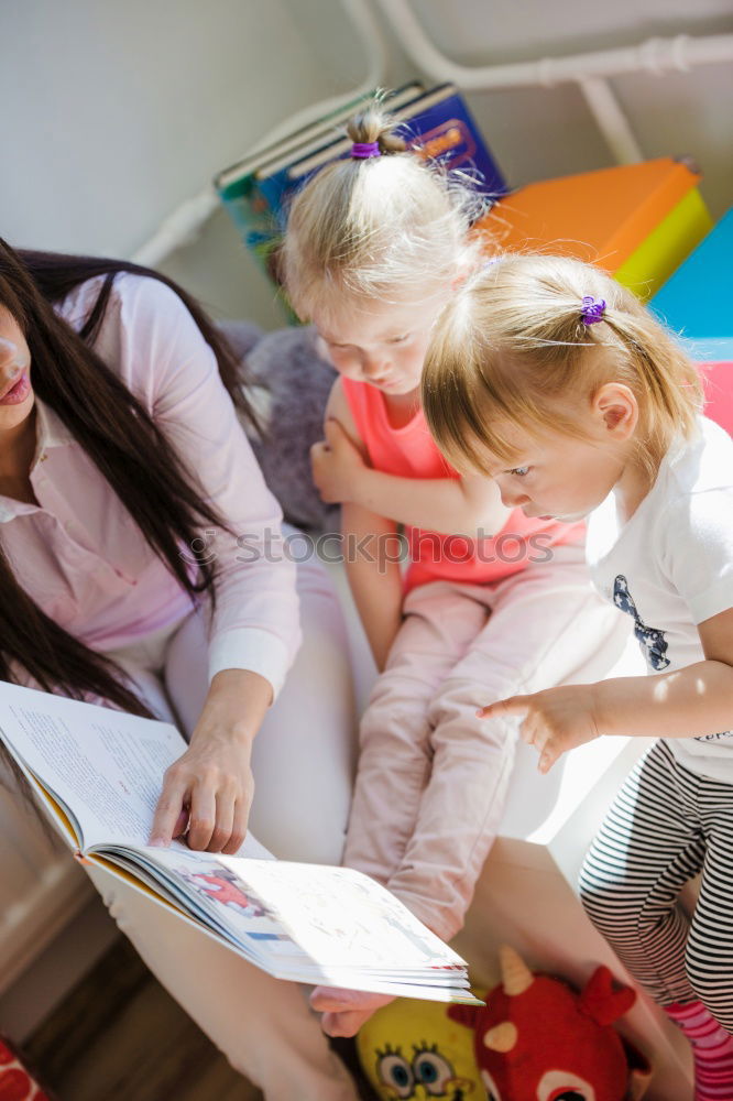 Similar – Girl and boy reading book sitting on bed