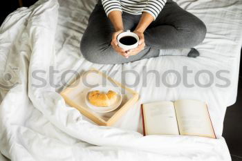 Image, Stock Photo woman reading a book and drinking coffee on bed with socks