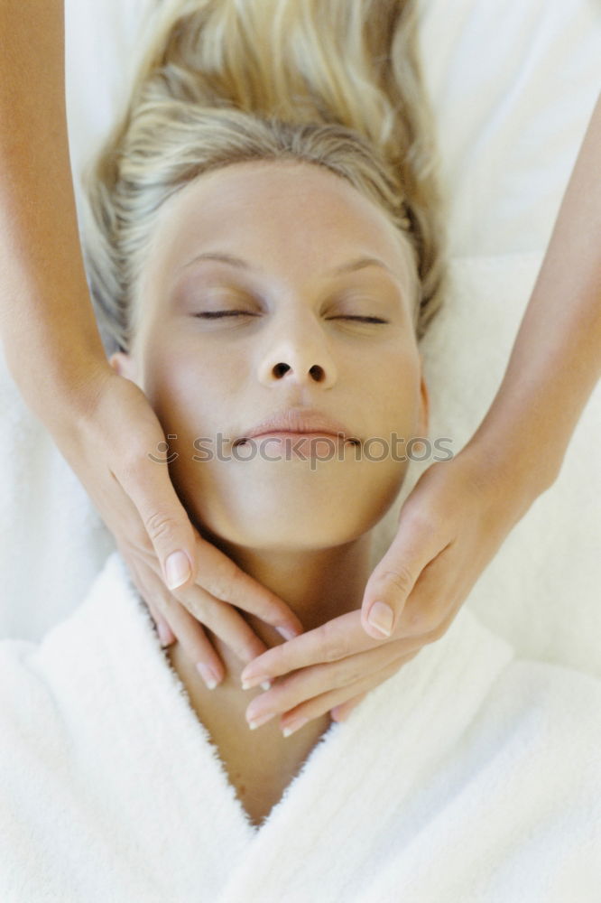 Young blond woman receiving a head massage in a spa center