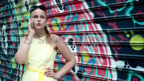 Similar – Image, Stock Photo Smiling woman in yellow dress standing and chatting on her smart phone in front of graffiti painted on corrugated iron