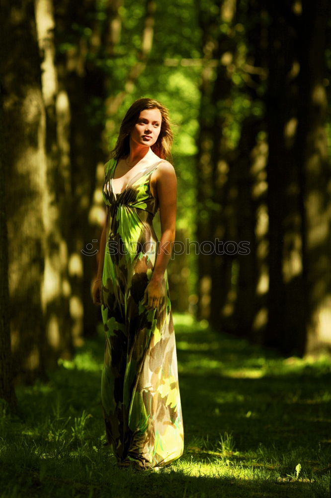 Similar – Young beautiful tall woman sitting barefoot on the ground in the forest looking at the camera against the sun