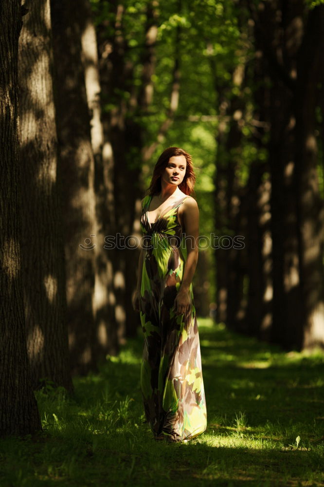 Similar – Young beautiful tall woman sitting barefoot on the ground in the forest looking at the camera against the sun