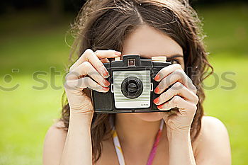 Similar – Smiling young woman using a camera to take photo at the park.