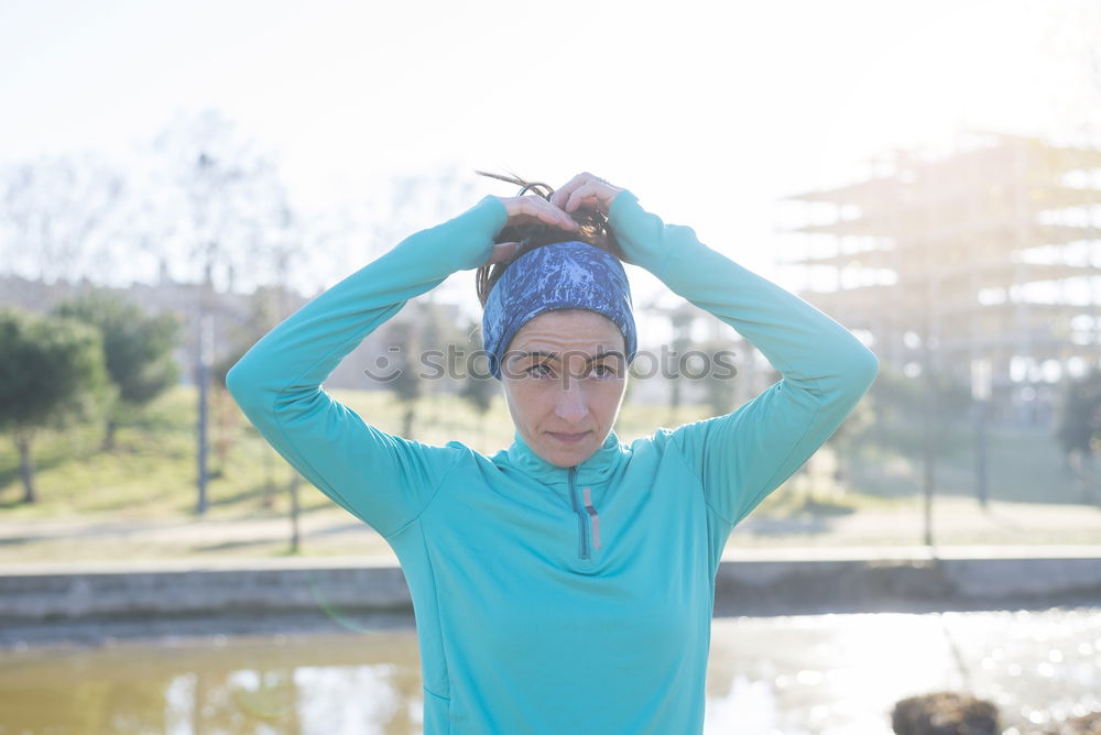 Woman tying hair in ponytail getting ready for run.