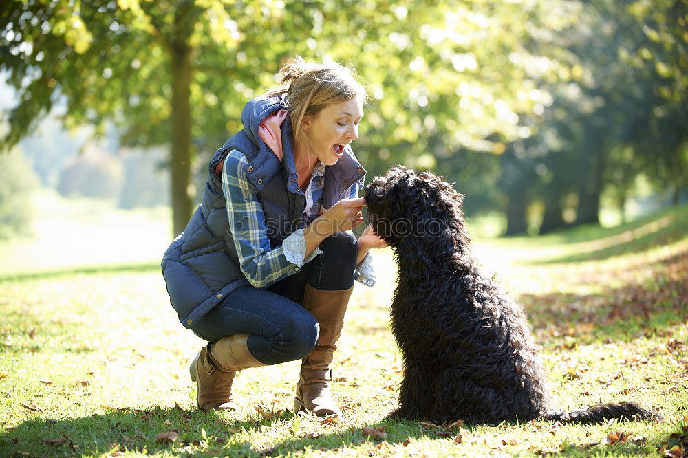 Similar – young woman with long brunette hair squats smiling on a meadow and looks at her dog