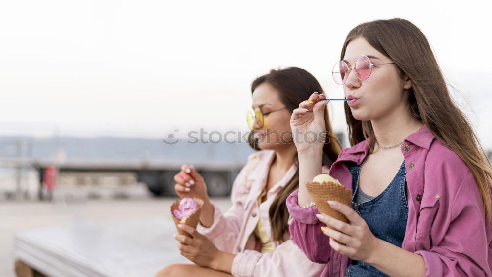 Girls eating ice cream on the promenade in summer holiday