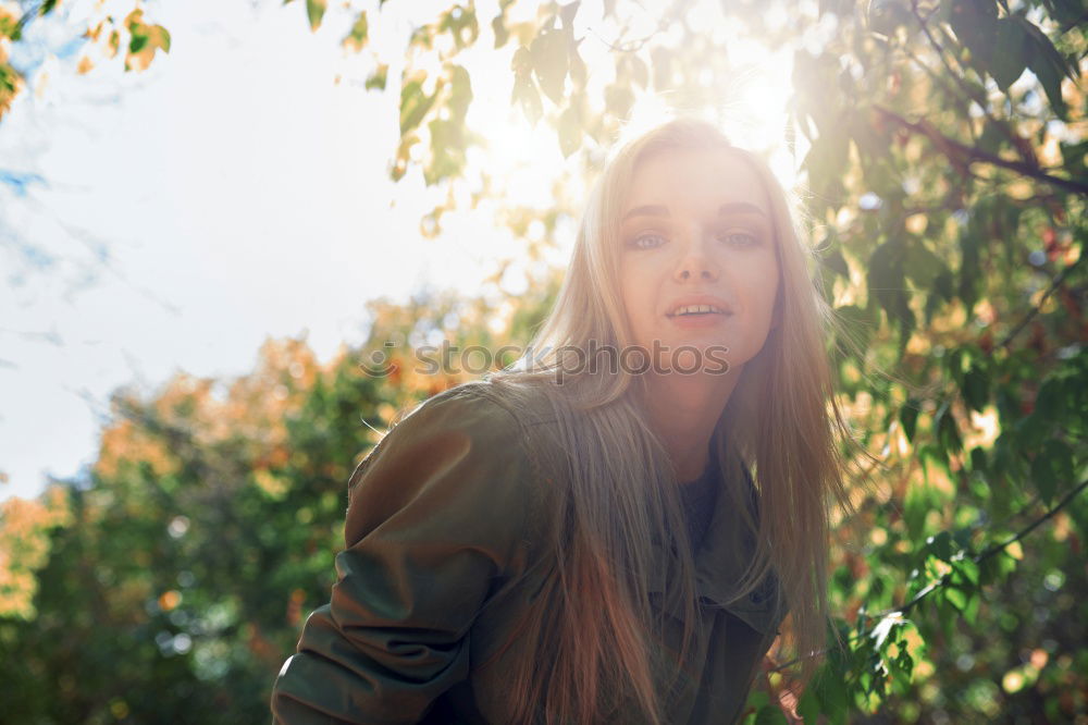 side portrait of young woman in summer dress sitting barefoot between bushes in nature