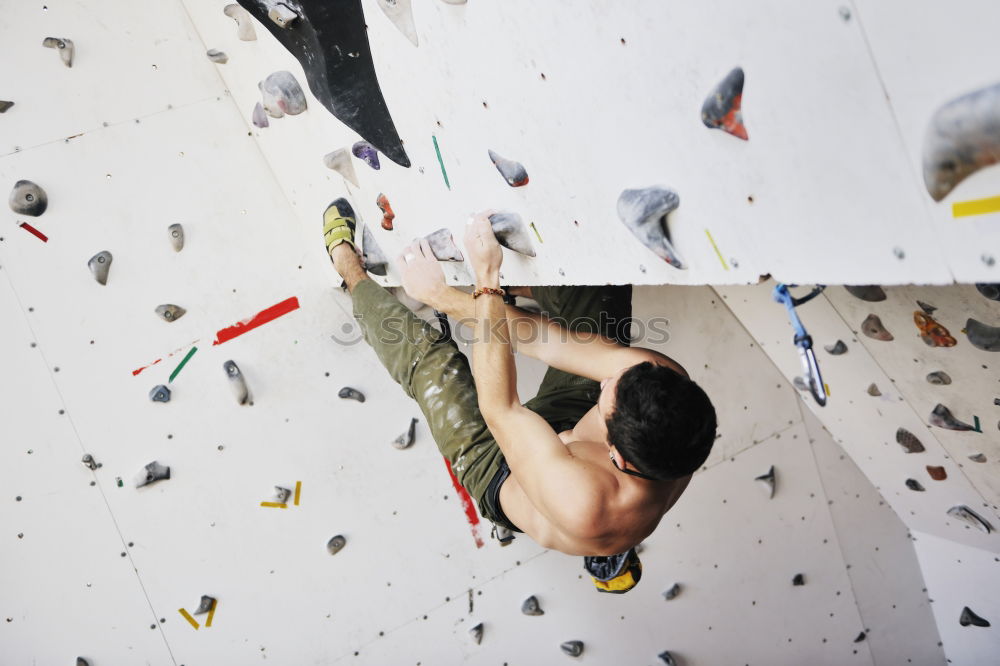 Man practicing rock climbing on artificial wall indoors.