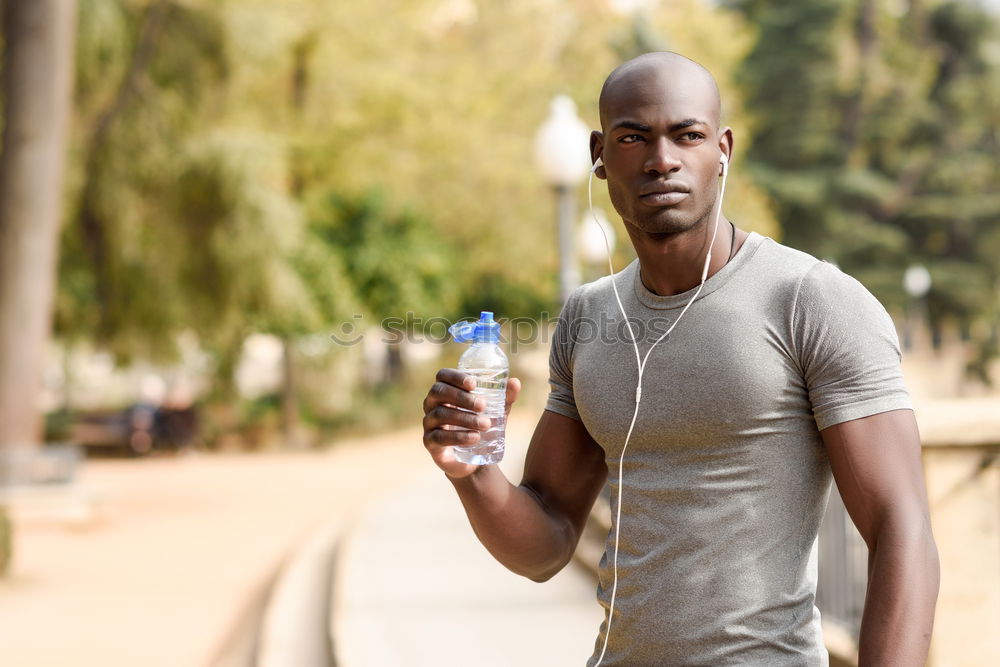 Young black man drinking water before running outdoors