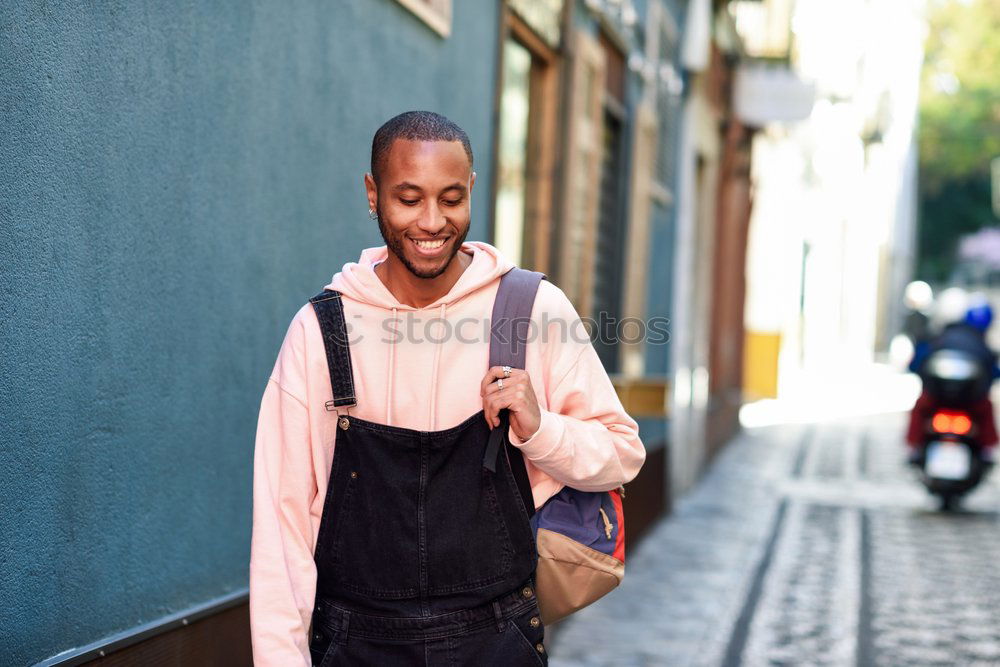 Young black man walking smiling down the street.