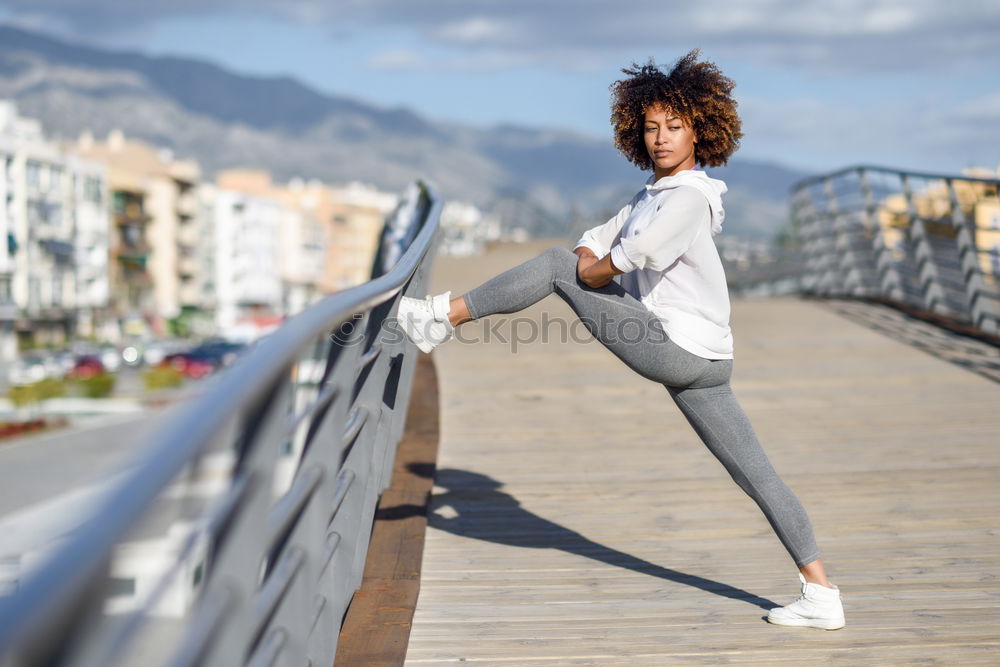 Young black woman doing stretching after running outdoors