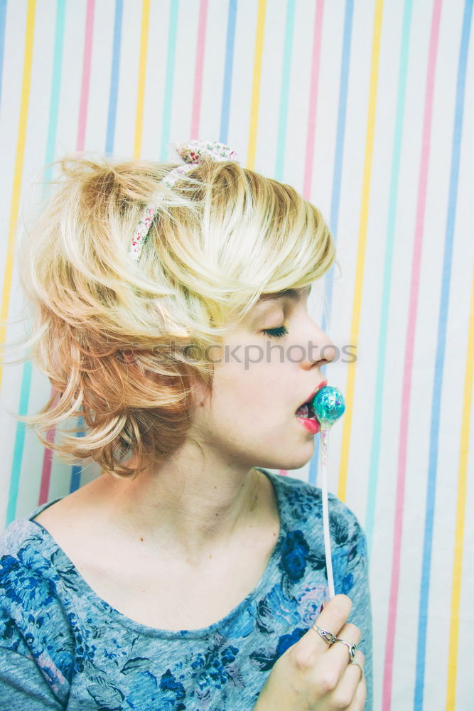 Young blonde woman biting a lollipop