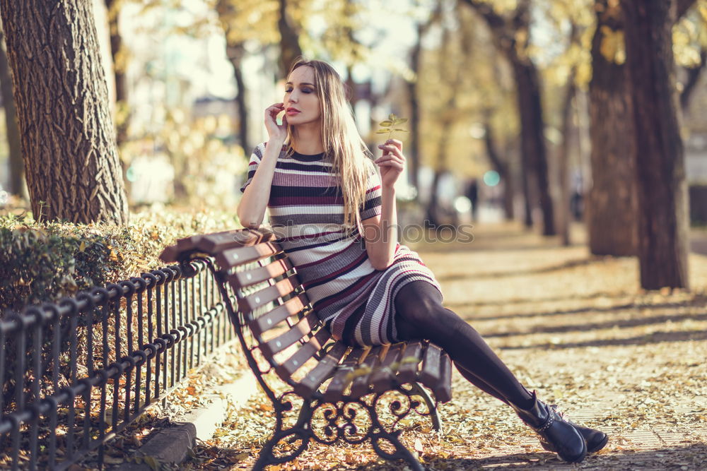 Young blonde woman sitting on a bench in the street