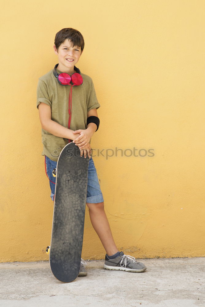 Similar – Image, Stock Photo Front view of young boy sitting on ground leaning on a yellow wall while using a mobile phone to listening music