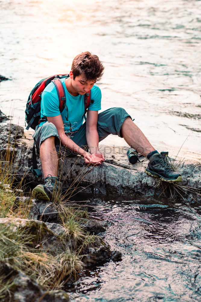 Young boy taking pure water from a river