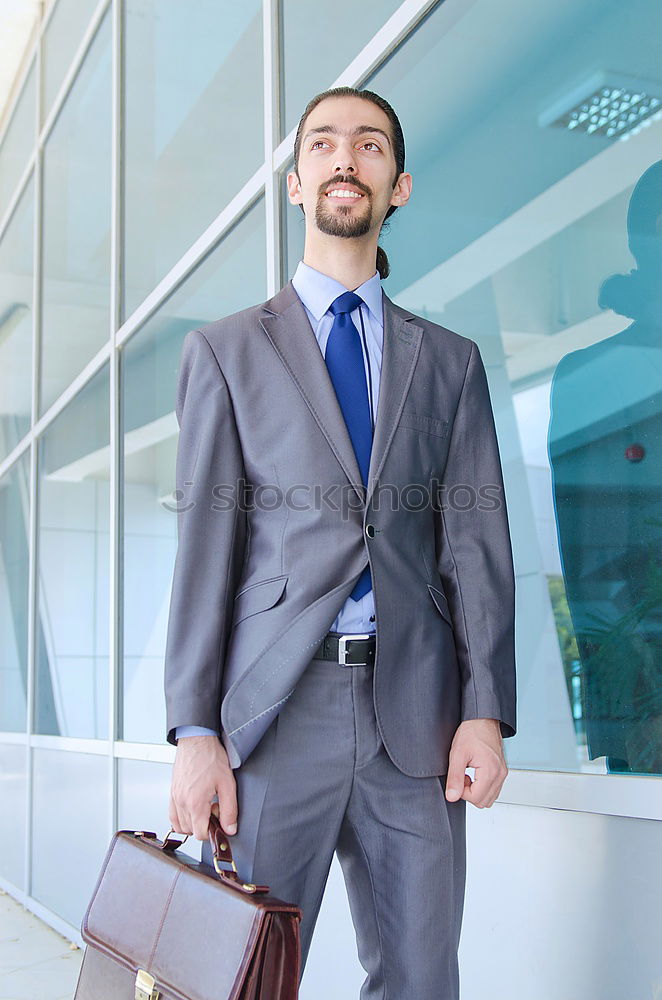 young businessman walking at the airport using his mobile phone