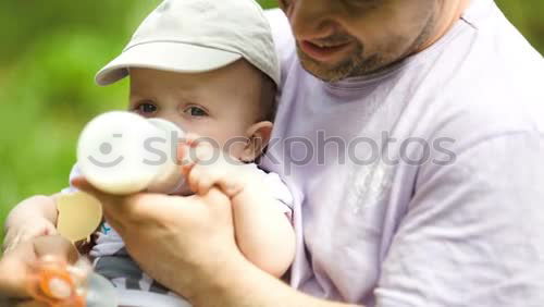 Similar – Image, Stock Photo Caring father feeding his baby son from the bottle in the park
