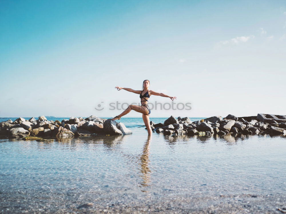 Similar – Girl with arms raised standing on the cliff