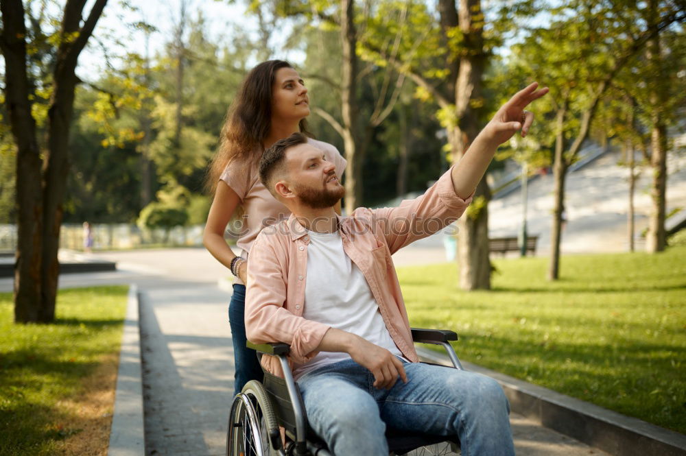 Woman and her friend in a wheelchair having stroll through the park at a river enjoying the autumn