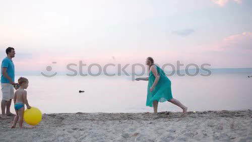 Similar – Image, Stock Photo Young family enjoying the sea at sunset paddling in the shallows together playing with the ball as they enjoy their summer vacation