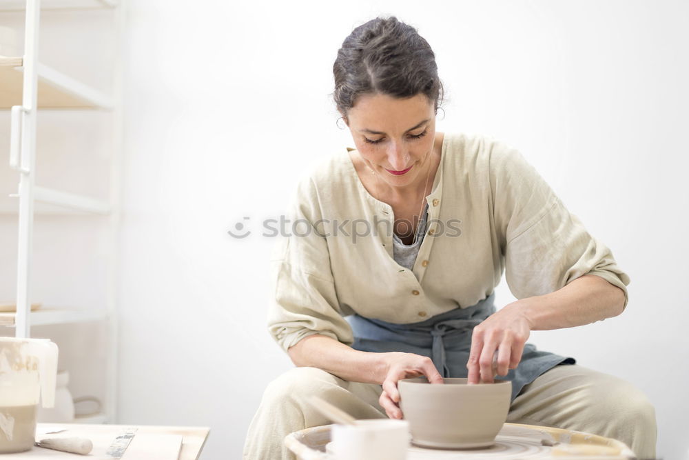 Image, Stock Photo Young female sitting by table and making clay or ceramic mug in her working studio