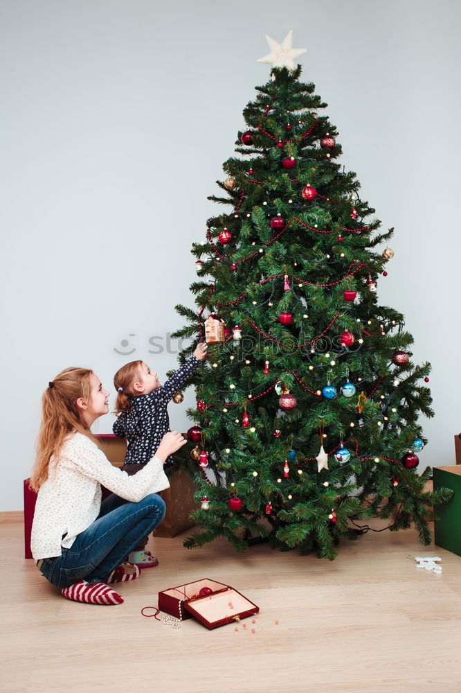 Young girl and her little sister decorating Christmas tree