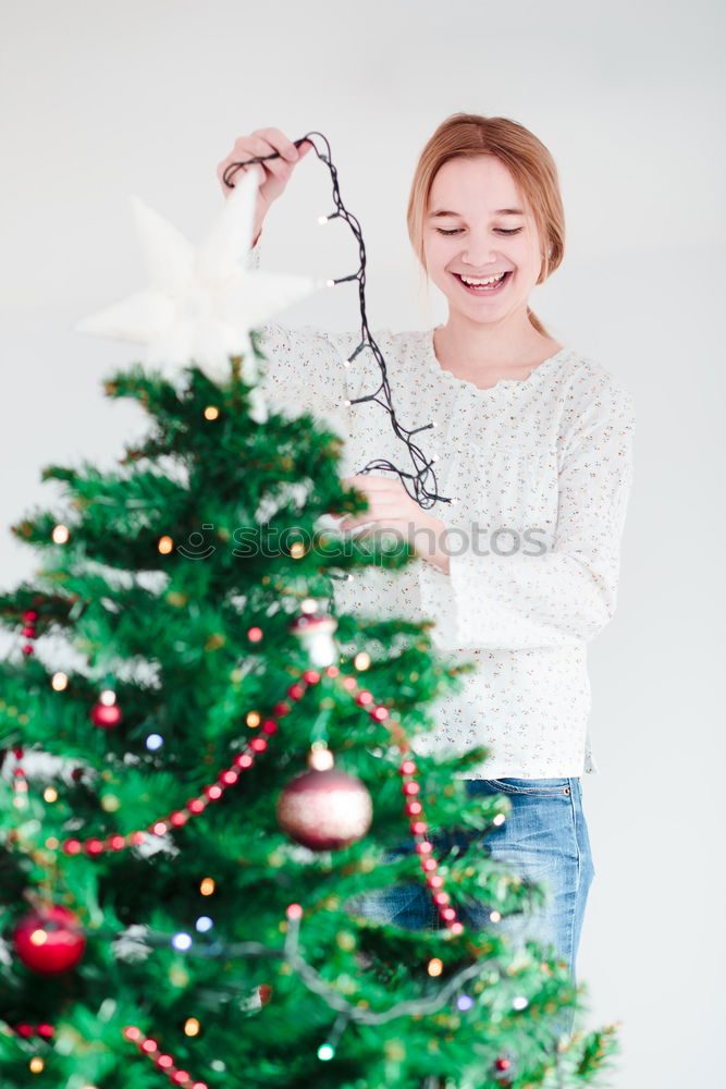 Image, Stock Photo Young girl decorating Christmas tree with lights at home