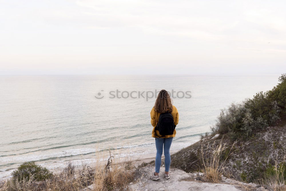 Similar – Rear view of a woman sitting on a wooden bench and looking at a lake