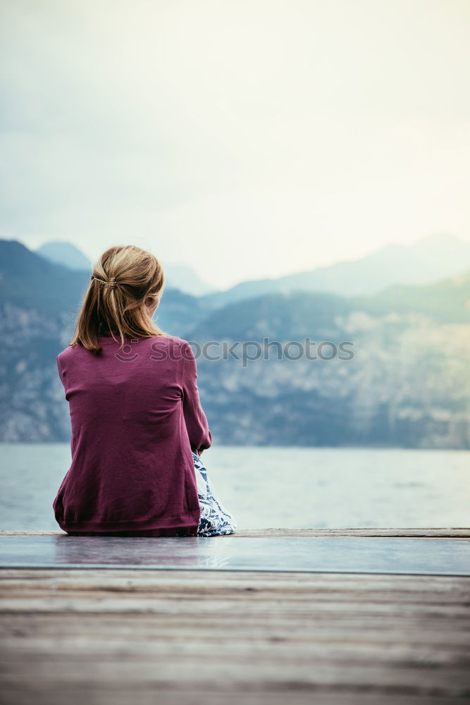 Similar – Thoughtful Woman Sits on Bench Facing at the River